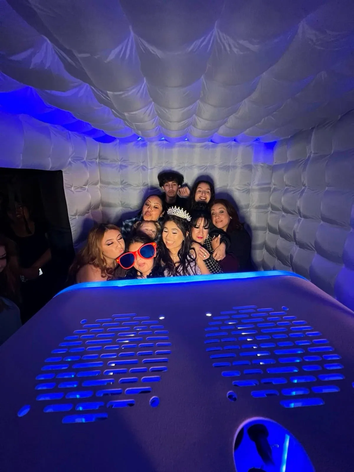 Guests posing together inside the lit photo booth during an event